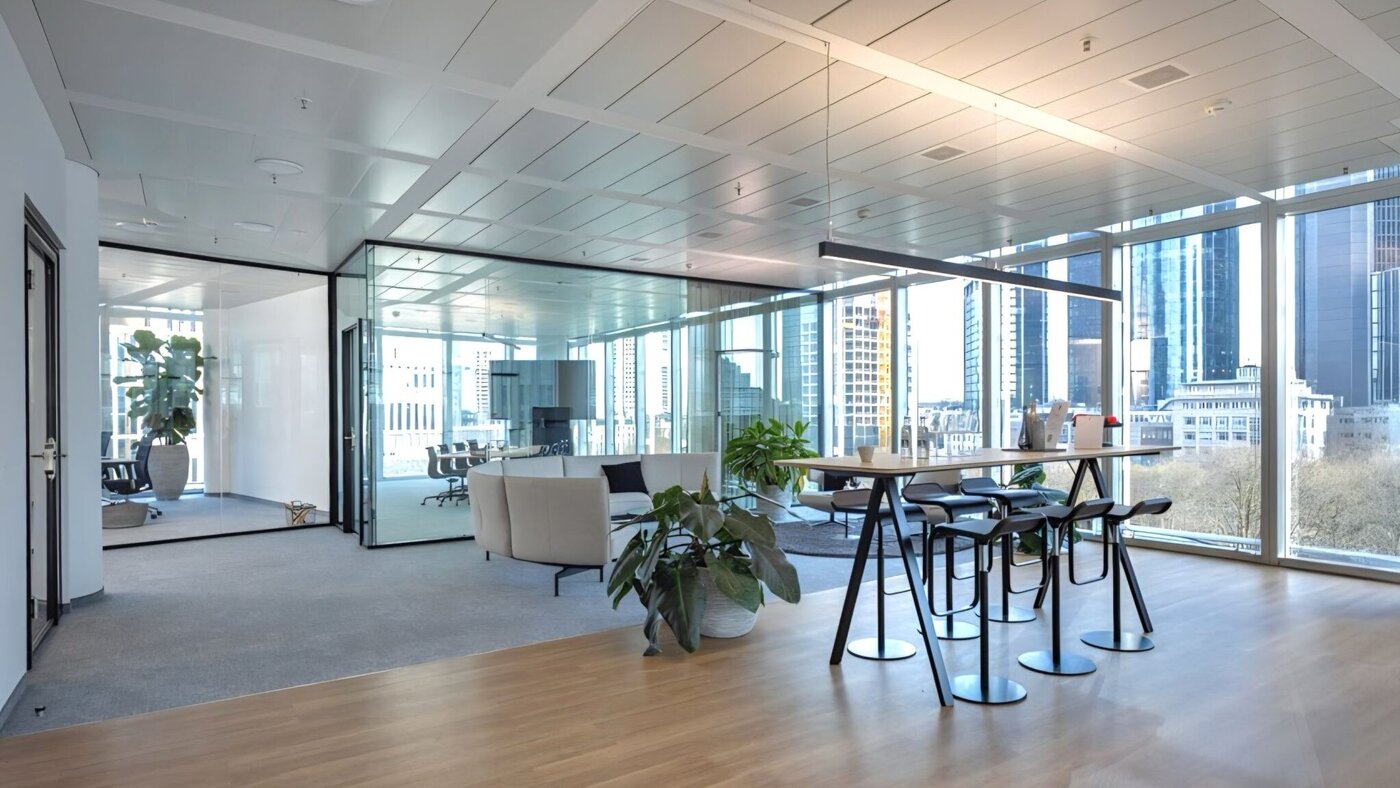 Offene Bürofläche im SKYPER Frankfurt mit Lounge, Meetingbereich, Hochtisch und bodentiefen Fenstern für Austausch und modernes Arbeiten.