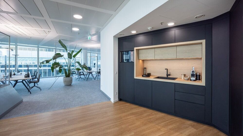Offene Teeküche im SKYPER Frankfurt mit angrenzenden Arbeitsplätzen, Glaswänden und flexiblem Bürokonzept für Austausch und kurze Wege.