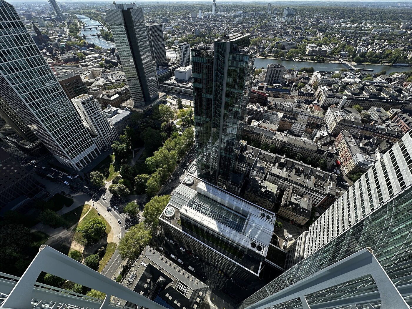 Blick vom SKYPER aus der Höhe auf Frankfurt mit Hochhäusern, Grünflächen, Innenstadt und Mainufer.