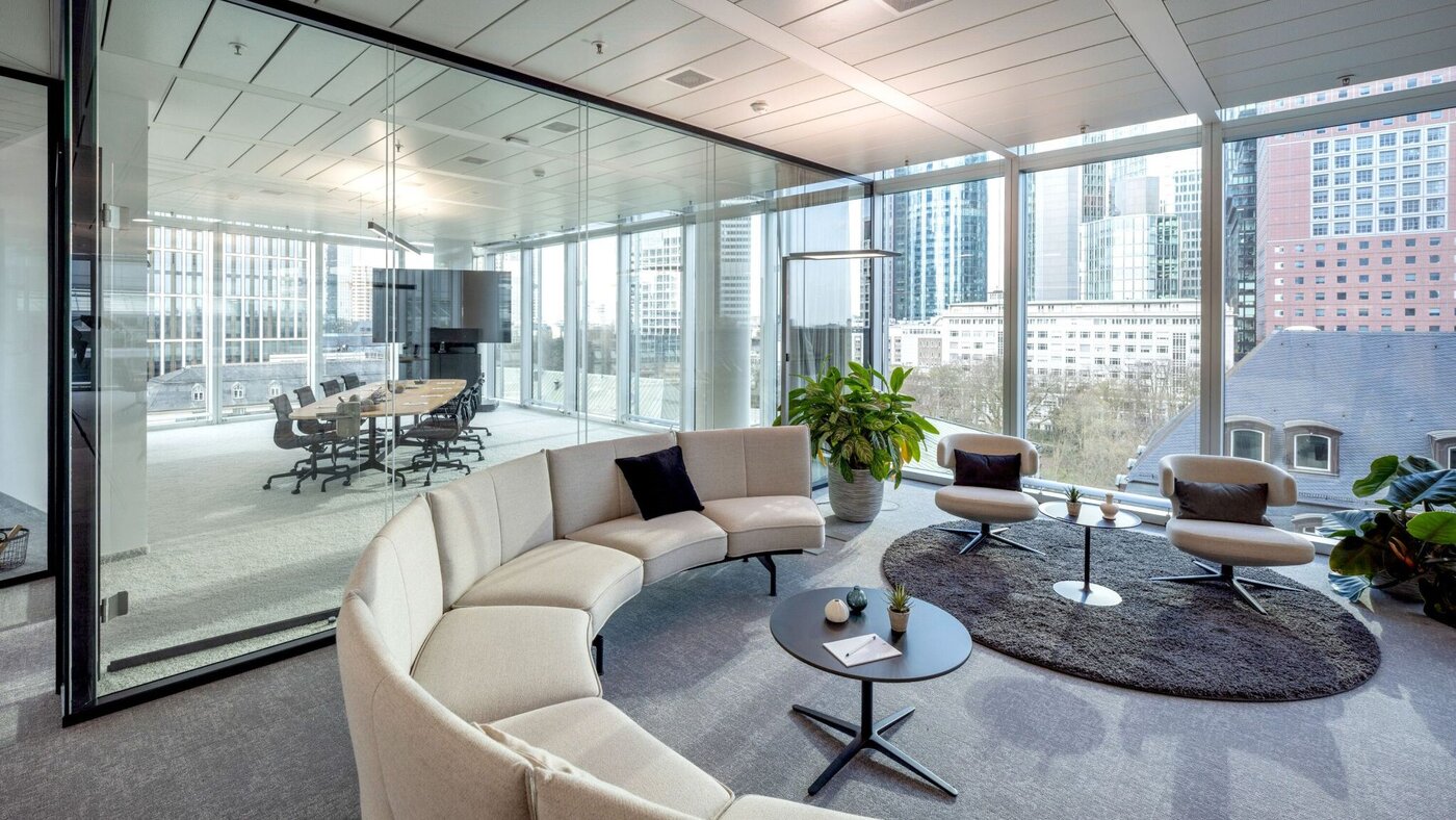 Moderne Lounge im SKYPER Frankfurt mit offenem Konferenzraum, Glaswänden, flexiblen Arbeitsbereichen und Blick auf die Frankfurter Skyline.