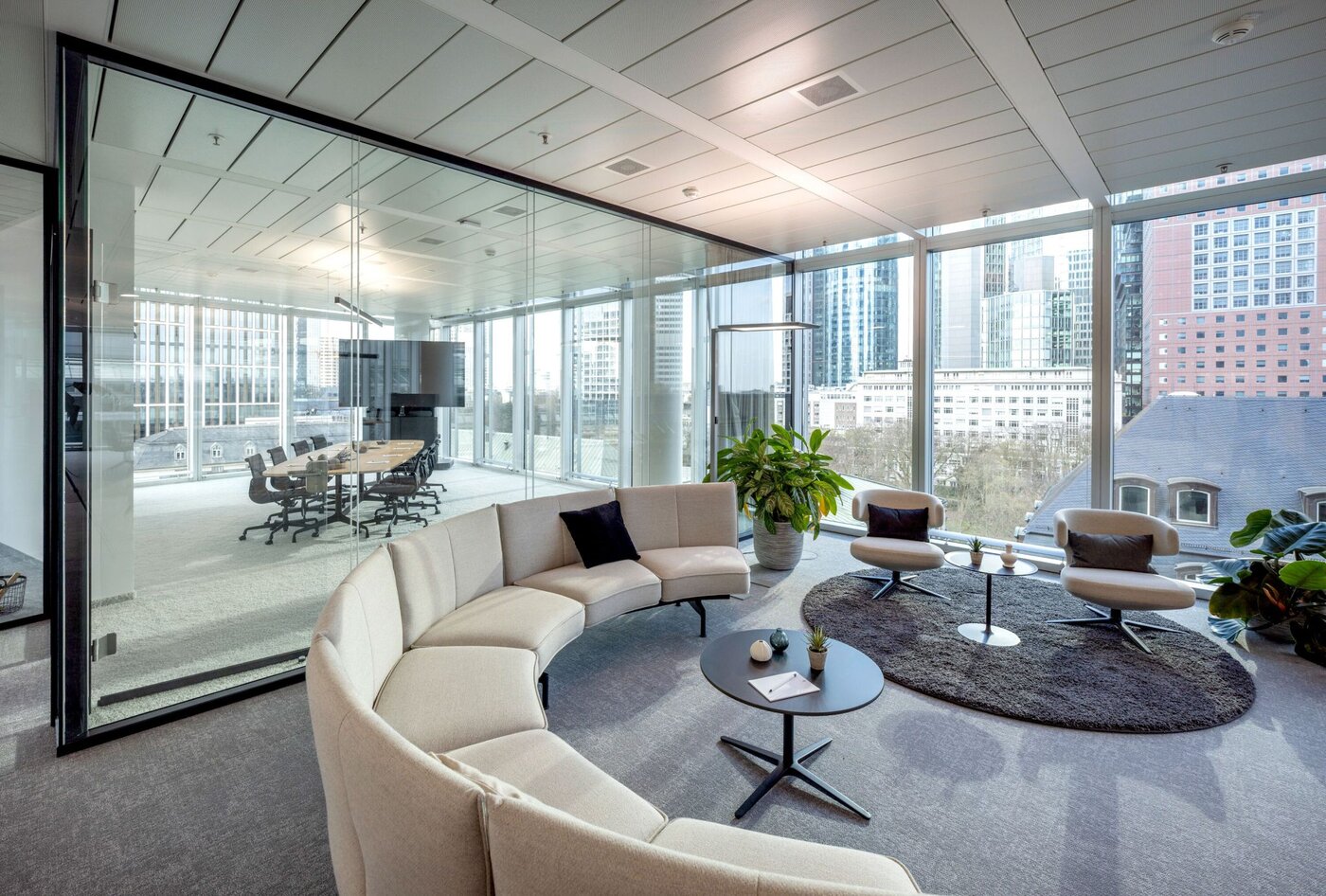 Modern lounge at SKYPER Frankfurt with open conference room, glass partitions, flexible work areas and views of the Frankfurt skyline.