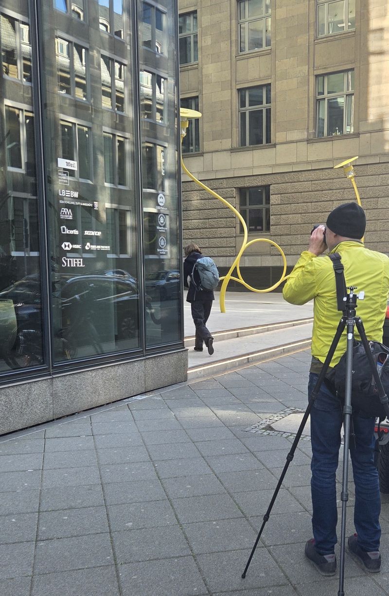 Fotograf vor dem SKYPER in Frankfurt mit Blick auf die moderne Glasfassade und die Skulptur Entangled Emotions von Jeppe Hein aus dem Jahr 2024.